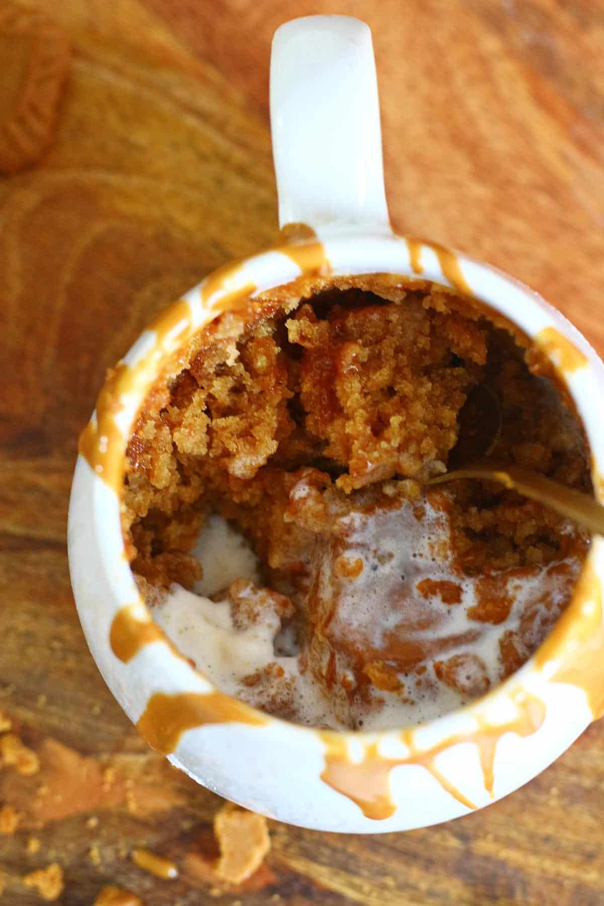 Inside view of Biscoff mug cake showing soft crumb with melted ice cream and Biscoff sauce.