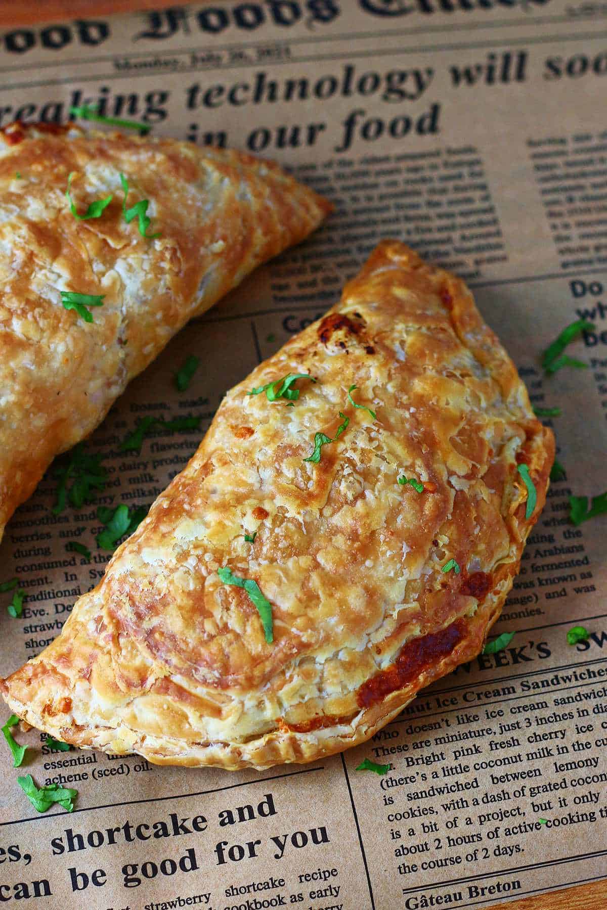 One golden paratha pocket on parchment paper with chopped cilantro on top.