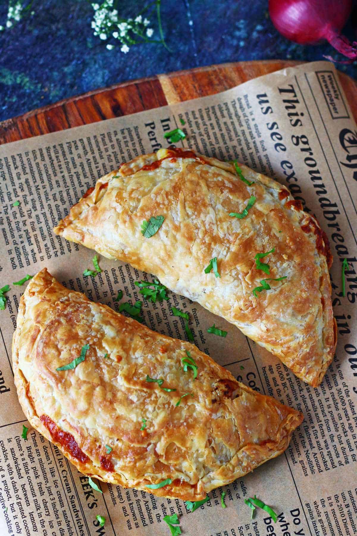 Two crispy paratha pockets on parchment paper with chopped cilantro.