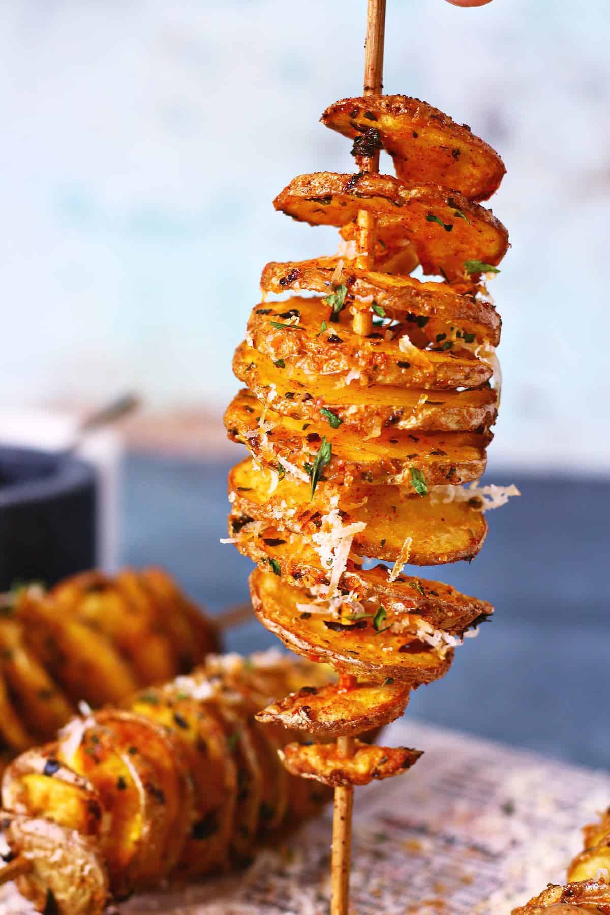 Spiral tornado potato on a skewer with crispy edges, seasoning, and grated parmesan.