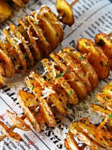 Close-up of sliced spiral potatoes on skewers with seasoning and grated cheese.