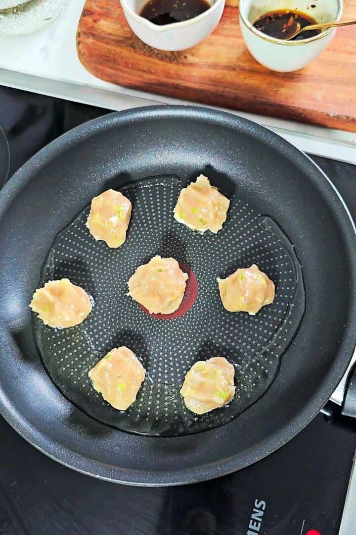 Small portions of chicken filling placed in a lightly oiled pan.