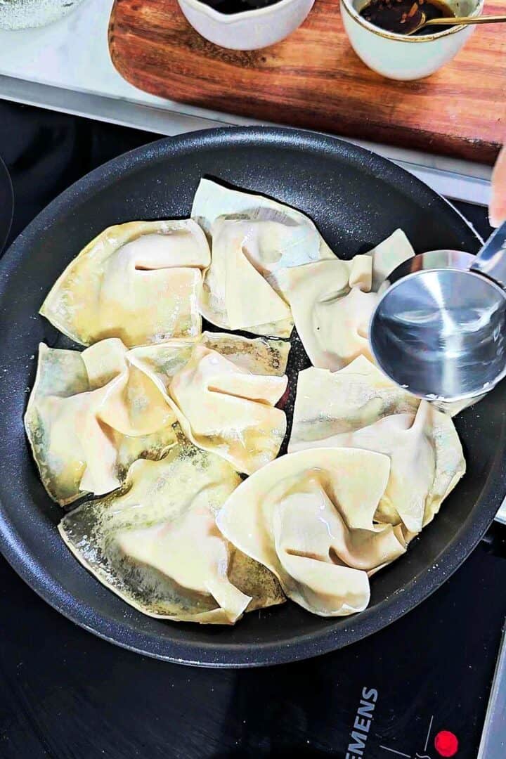 Wonton wrappers placed over chicken filling and gently pressed around.