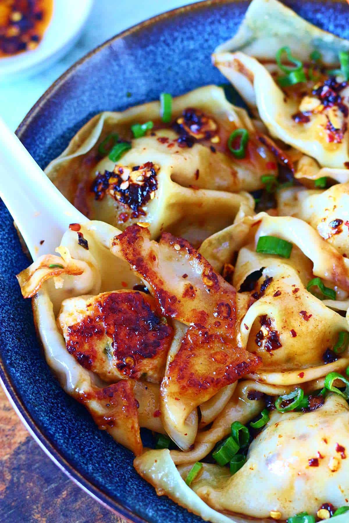 Close-up of a blanket dumpling showing crispy bottoms and chili flakes.