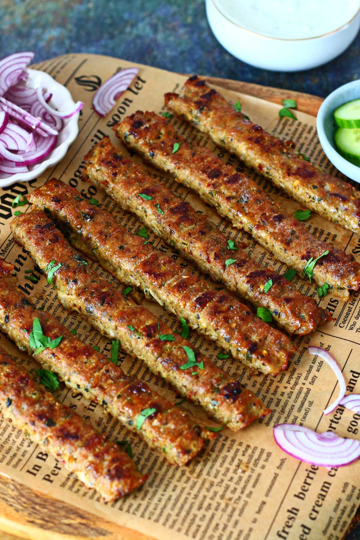 Sheet pan kebabs served on a wooden board lined with parchment, garnished with herbs and onions.