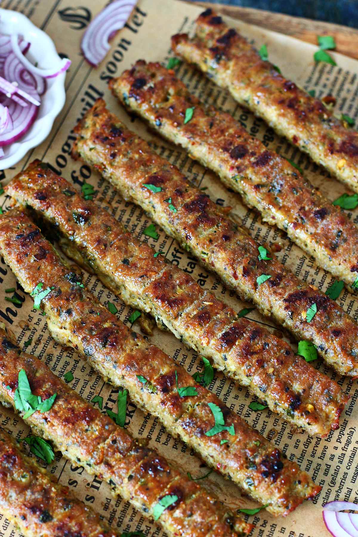 Close-up of browned sheet pan kebabs with charred edges and chopped cilantro on top.