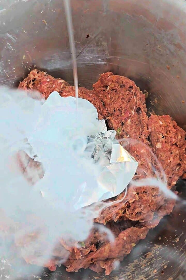 Charcoal smoking a seasoned beef kabab mixture in a metal bowl.