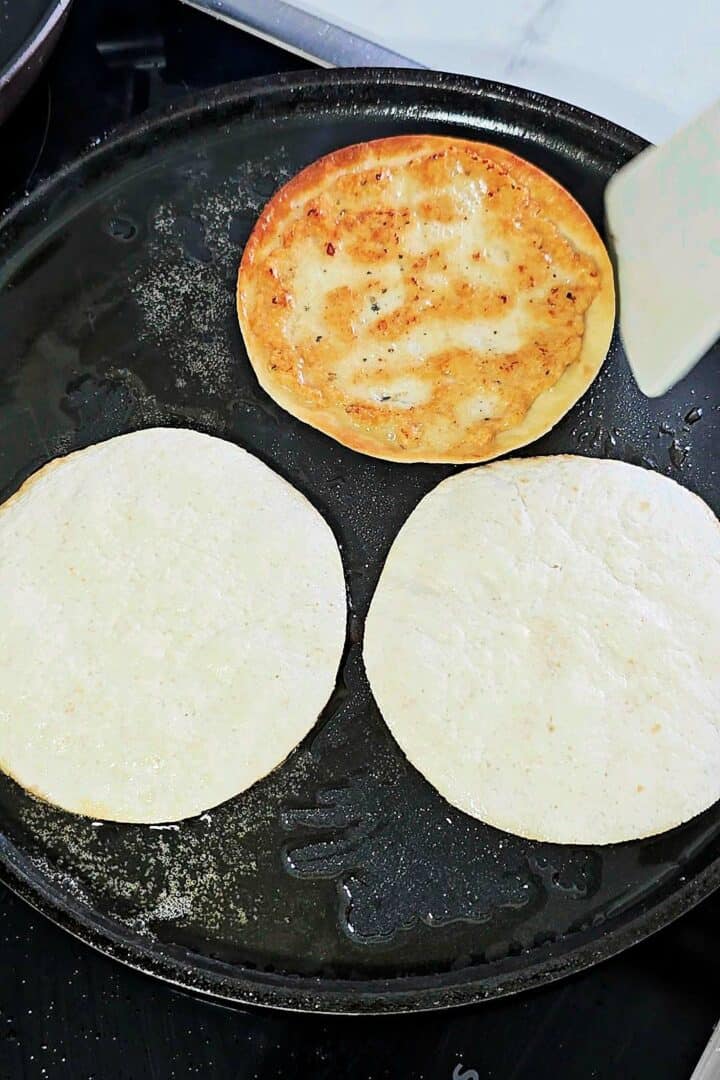Chicken smash tacos cooking chicken-side down in a skillet until golden brown.