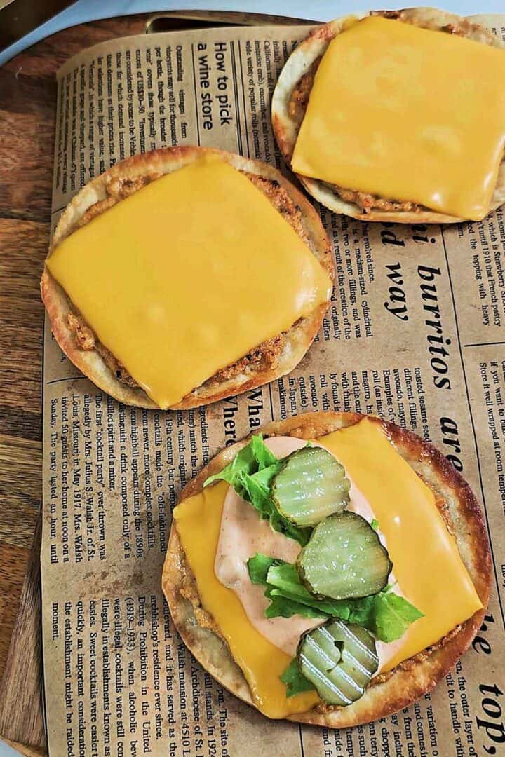 Chicken Big Mac smash tacos topped with melted cheese, lettuce, pickles, and creamy sauce on parchment paper.