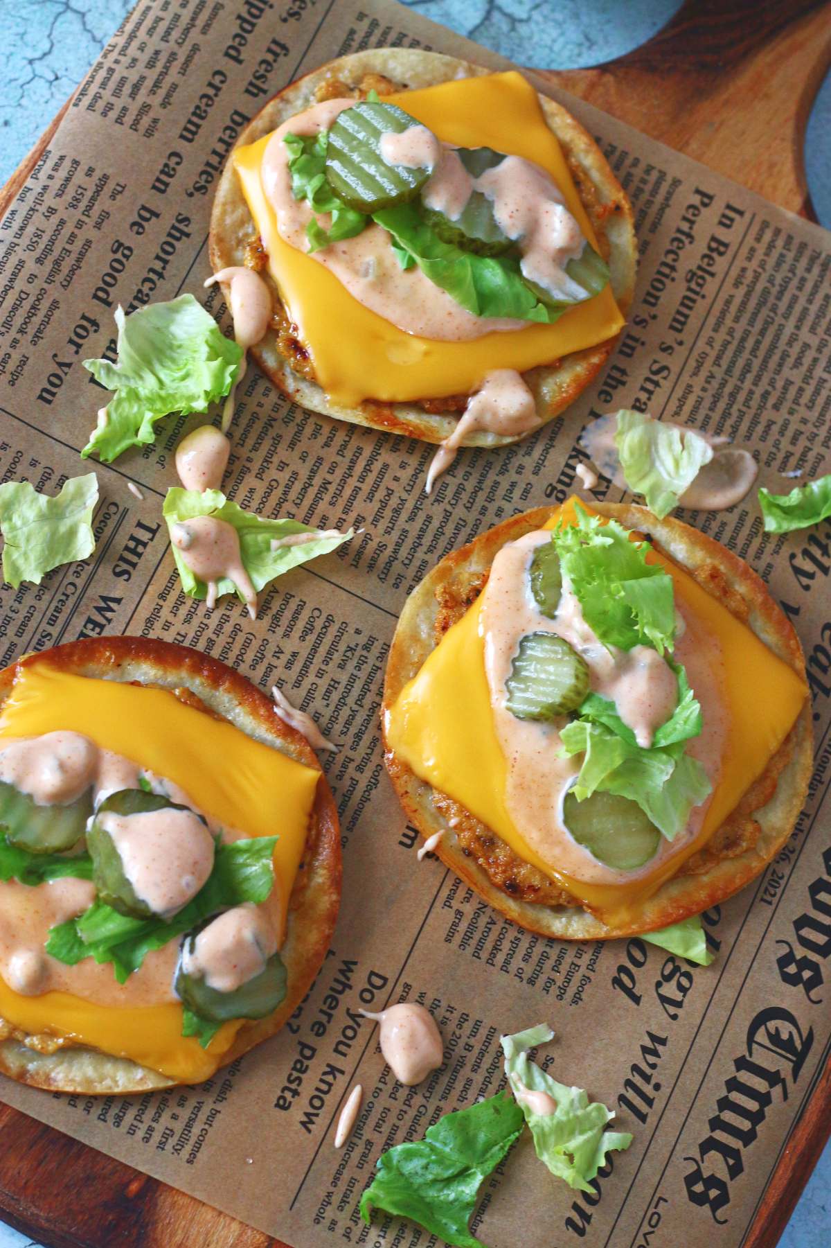 Chicken Big Mac smash tacos topped with melted cheese, lettuce, pickles, and creamy sauce on a wooden serving board.