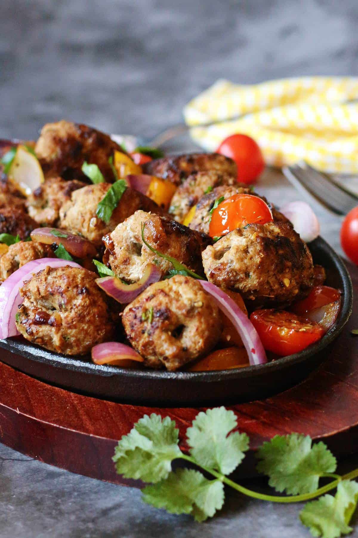Close-up of Pakistani gola kababs with sautéed vegetables and fresh cilantro garnish.