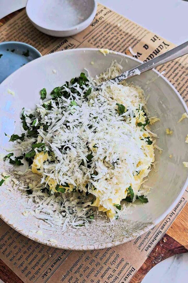 Butter, Parmesan, garlic, and parsley mixed in a white bowl.