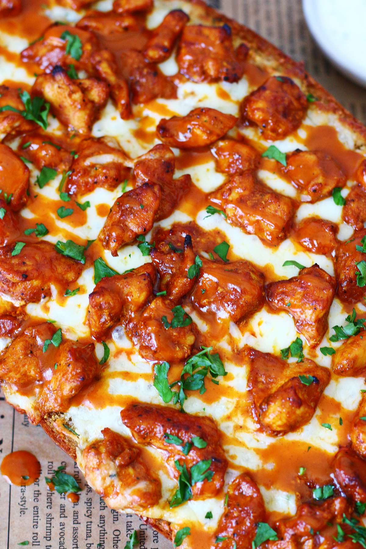 Buffalo chicken garlic bread topped with melted mozzarella, buffalo chicken, buffalo sauce, and chopped parsley.