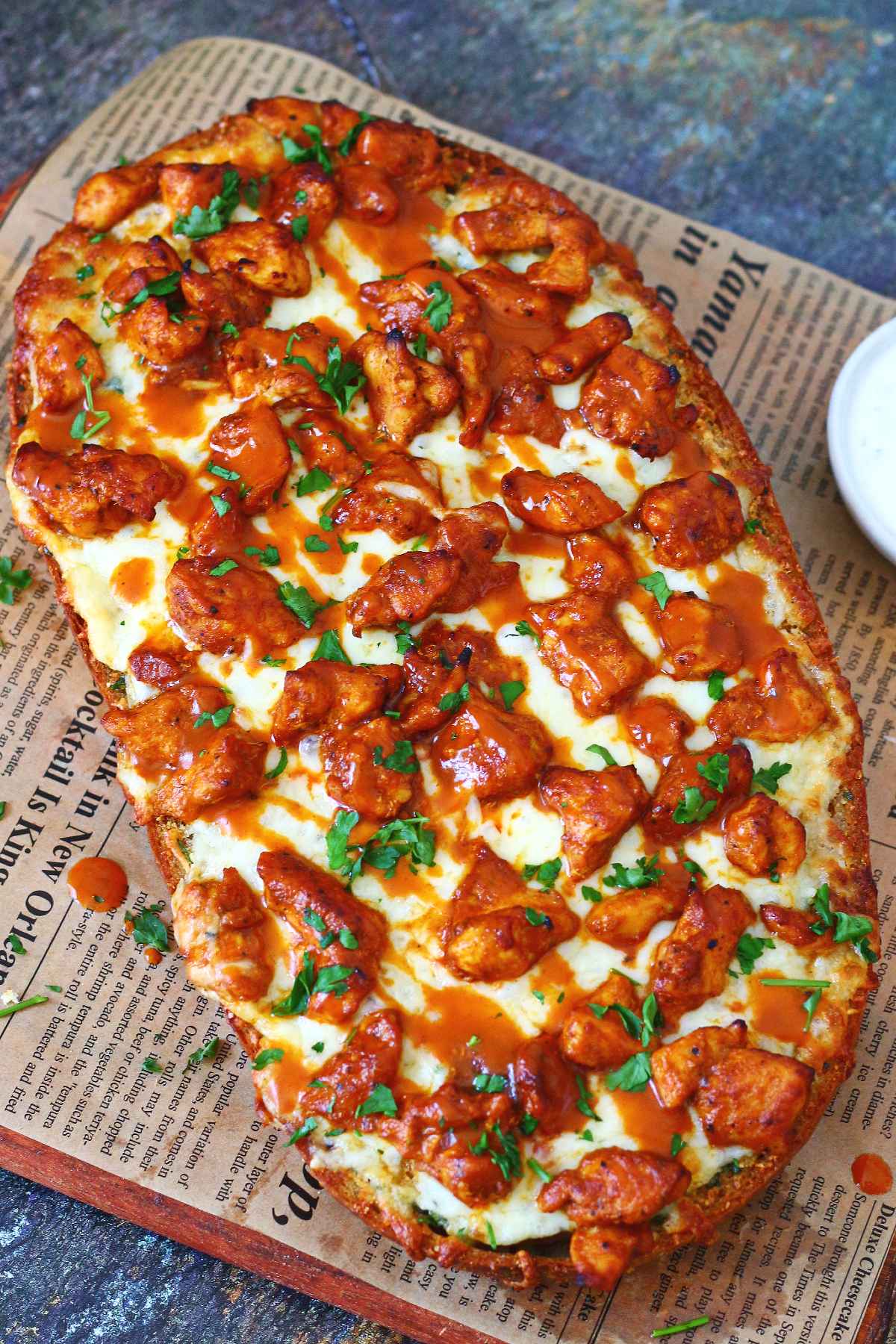 Whole buffalo chicken garlic bread topped with melted mozzarella, buffalo chicken, buffalo sauce, and chopped parsley.