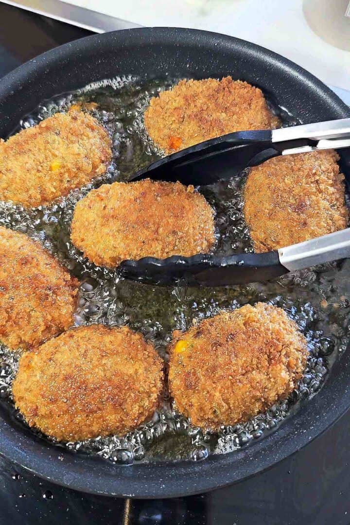 Golden brown chicken croquettes frying in oil.