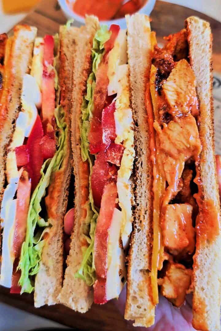 Cross-section showing the layers of a tandoori chicken club sandwich.