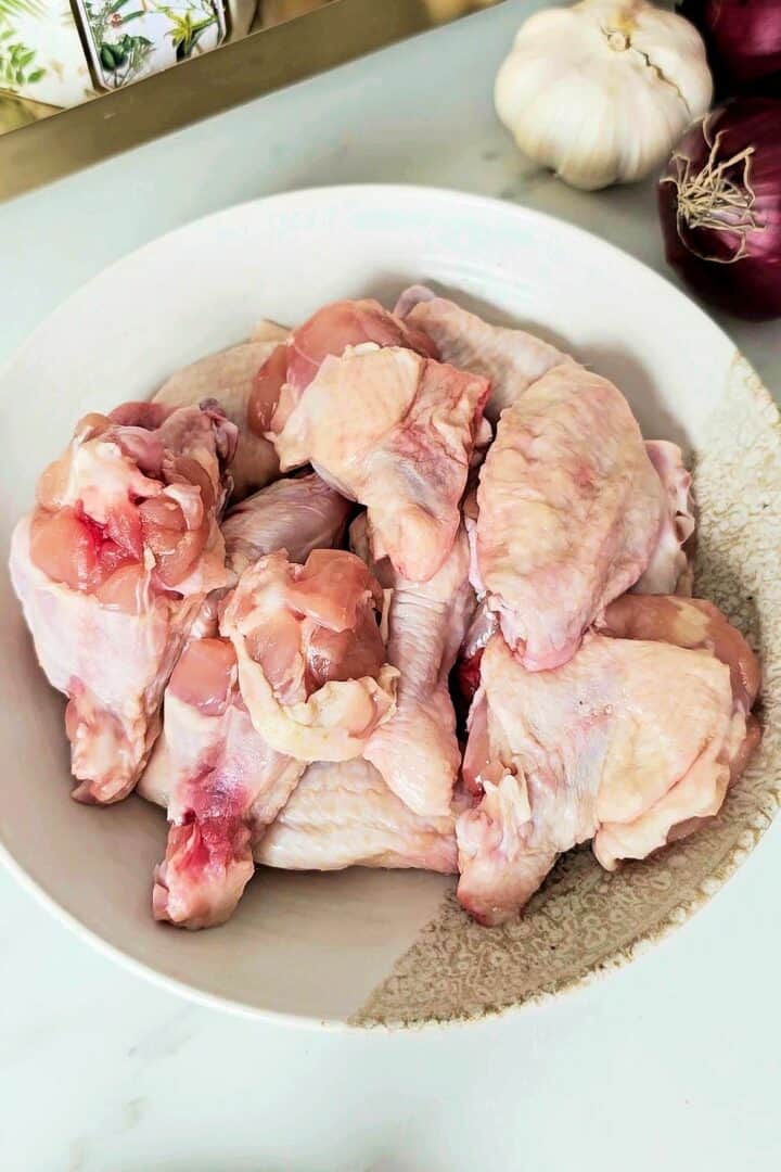 Raw chicken wings split into drumettes and flats in a shallow plate.