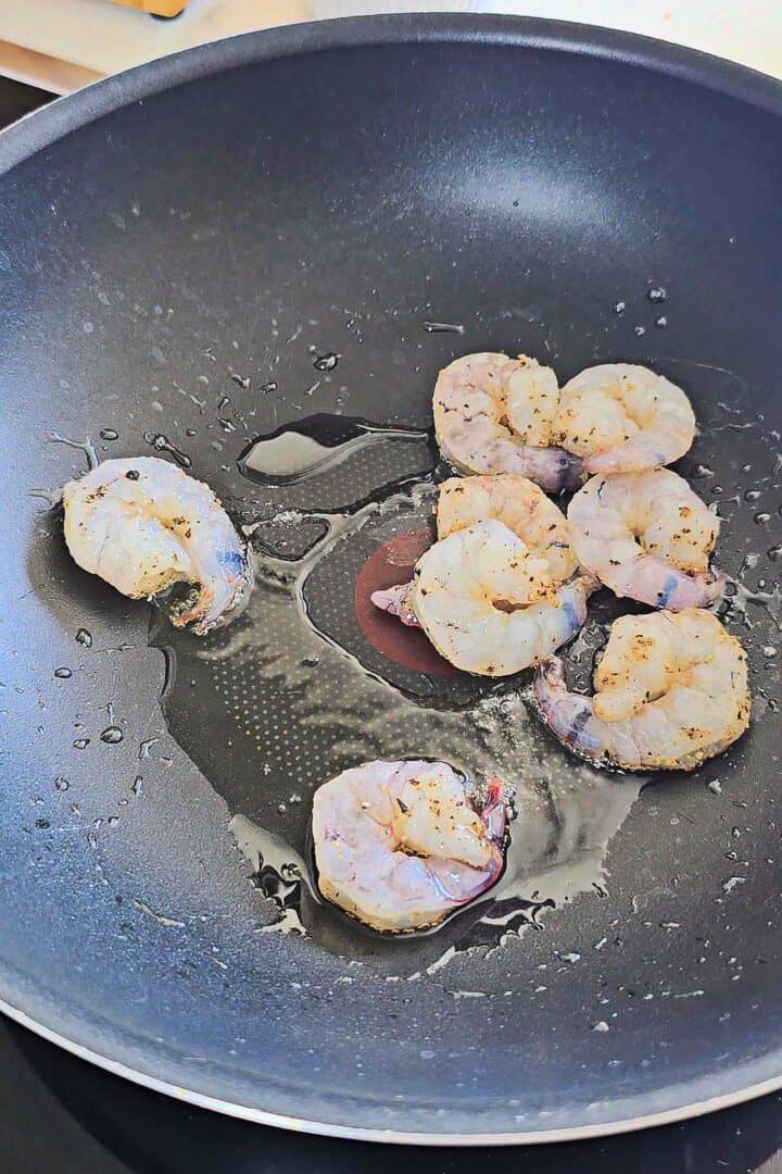 Seasoned shrimp searing in a hot wok.