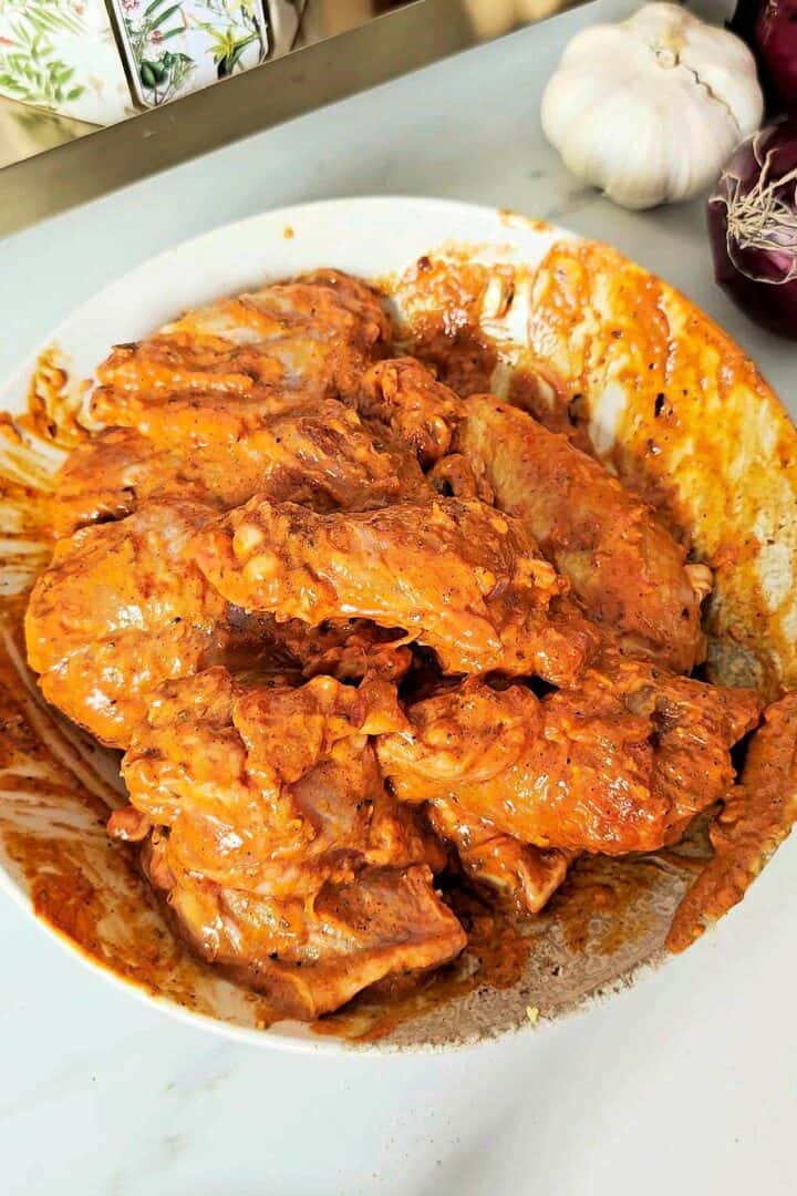 Fully coated tandoori chicken wings marinated in yogurt and spices before refrigerating.