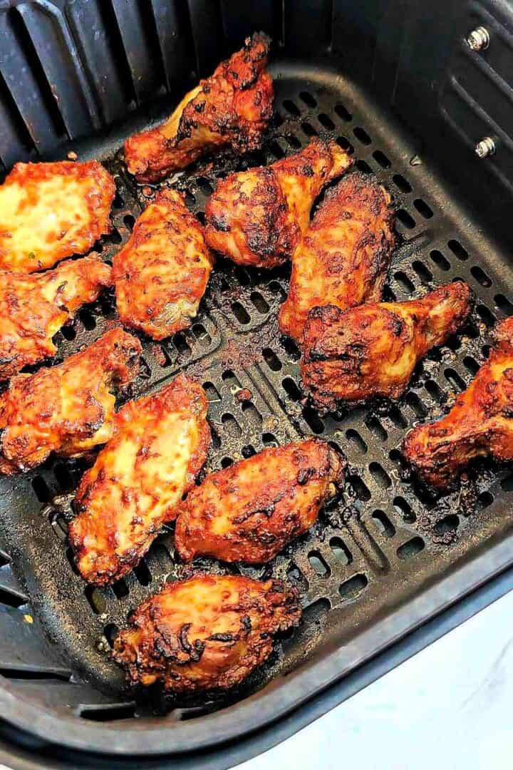 Air fryer tandoori chicken wings cooked and charred in the basket.