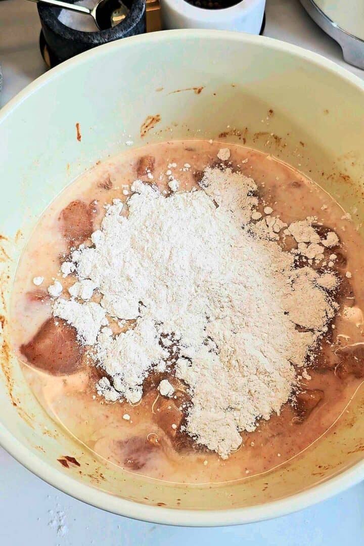 A few spoonfuls of seasoned flour added to the marinated chicken in buttermilk.
