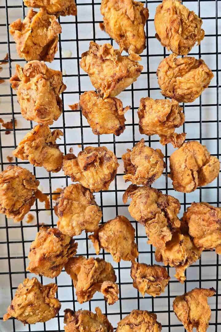 Crispy fried chicken pieces draining on a wire rack.