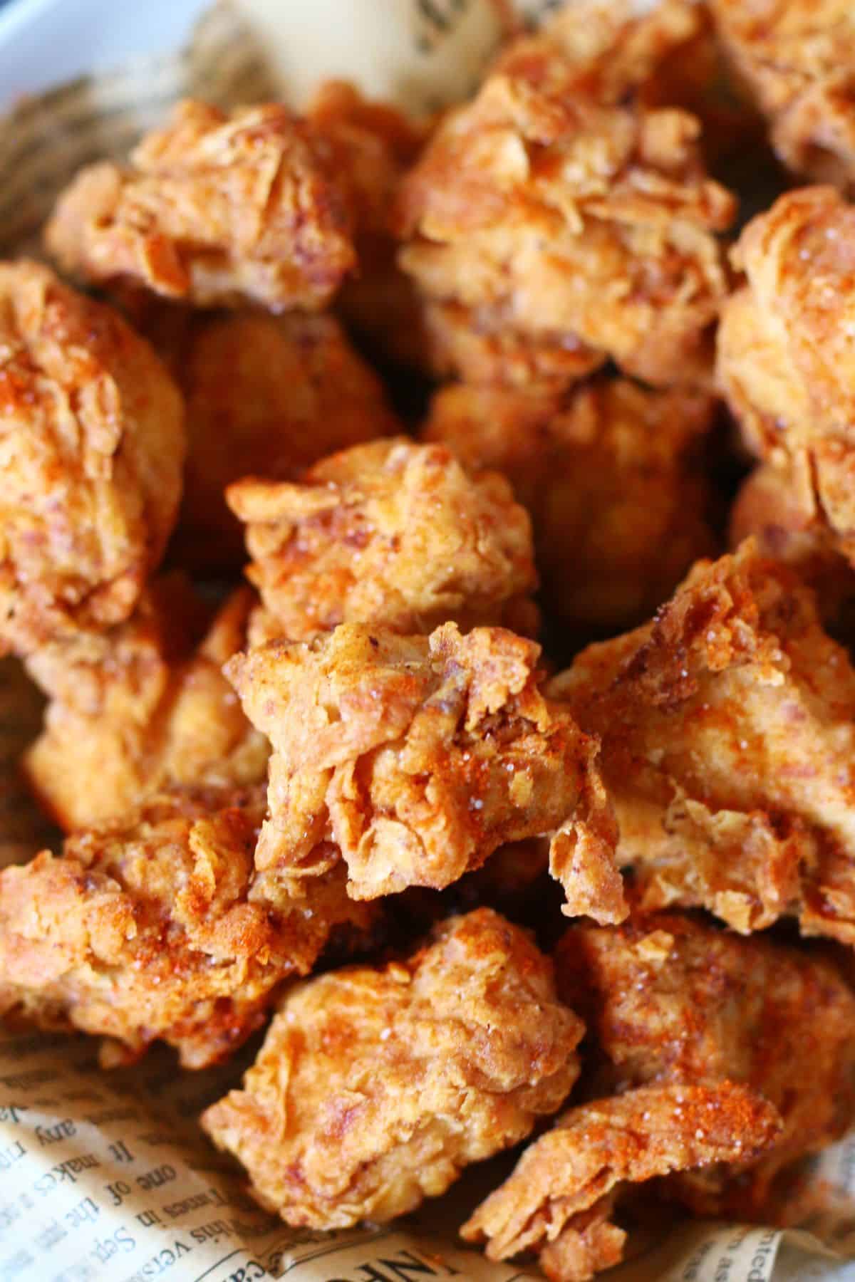 Close-up of crispy, craggy popcorn chicken pieces dusted with cayenne and salt.